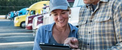 woman using a tablet in front of trucks 