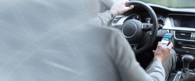 driver with hand on wheel using phone