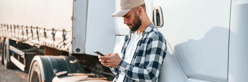 man using mobile phone next to a semi