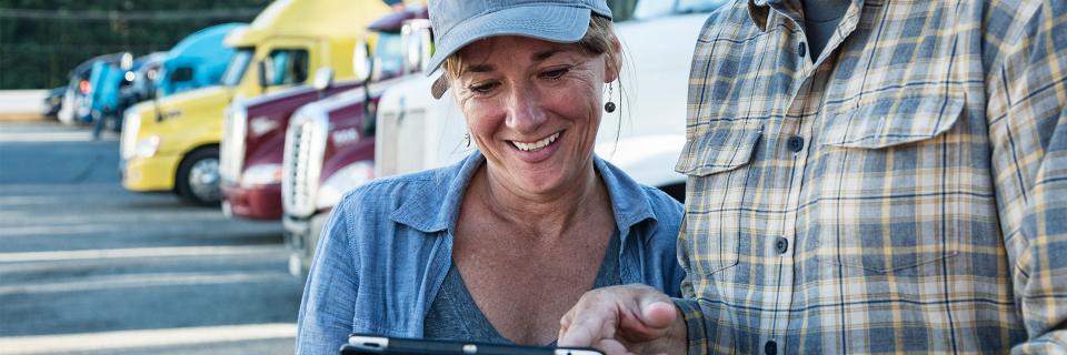 woman using a tablet in front of trucks