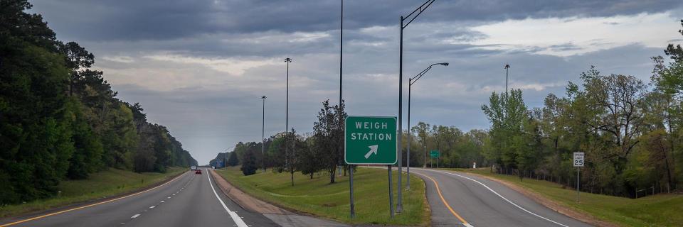 weigh station sign between two roads