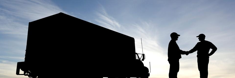 silhouette photo of two people shaking hands next to truck