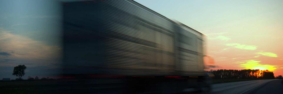 truck driving down highway with sunset